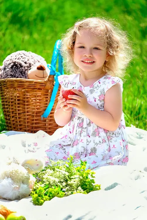 petite fille assisse avec une pomme en main